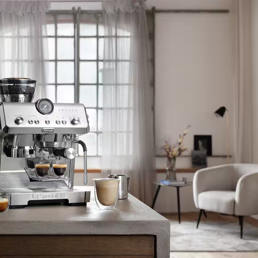 Espresso machine on a wooden table with a blurred living room background