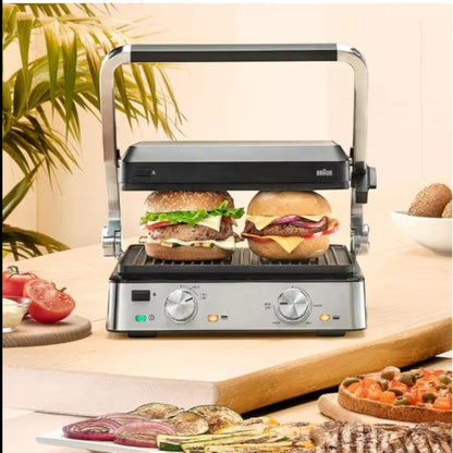 Taghareed Braun MultiGrill 7 CG7020 2000W contact grill with two burgers cooking. Stainless steel and black.