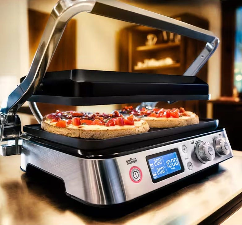 Taghareed Braun MultiGrill 9 CG9040 contact grill with two pizzas cooking on non-stick plates. Stainless steel finish.