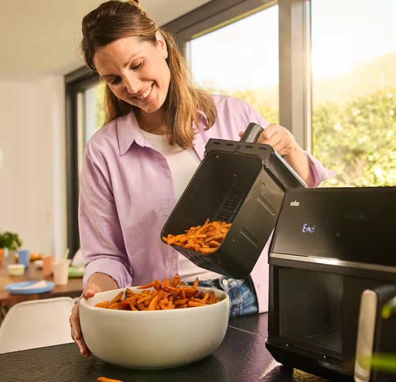 Taghareed woman pouring sweet potato fries from a Braun TwinCook 5 air fryer basket into a white bowl.
