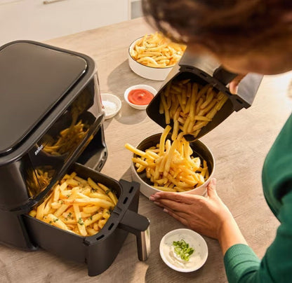 Braun TwinCook 3 dual basket air fryer in black, pouring fries into a bowl. 8L capacity.