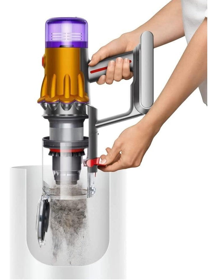 Taghareed cordless stick vacuum cleaner with yellow and purple accents, emptying dust bin. Lightweight and versatile.