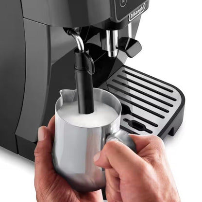 Taghareed De’Longhi Magnifica Start coffee machine frothing milk in a stainless steel pitcher. Black automatic espresso maker.