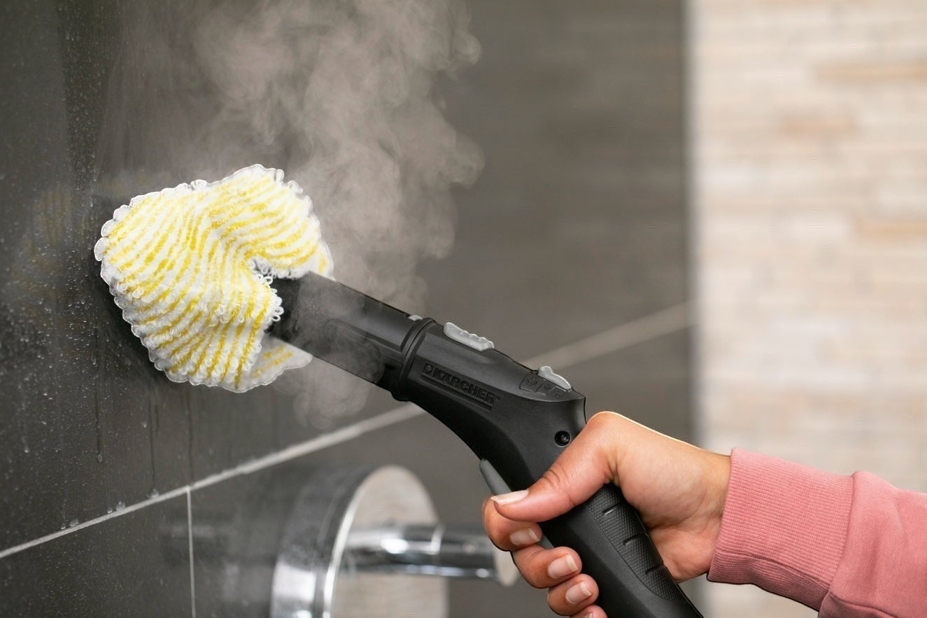 Taghareed Karcher SC 4 EasyFix steam cleaner with yellow and white microfiber pad cleaning dark tiled wall.
