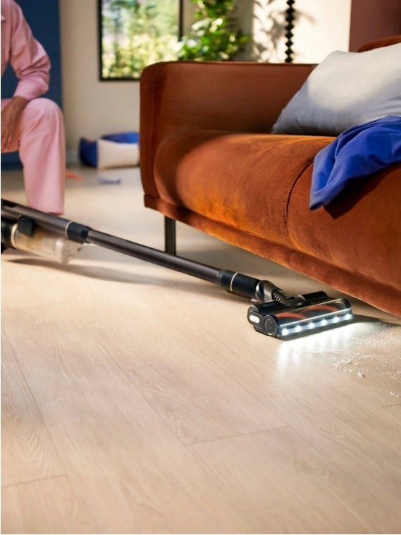 Taghareed Philips 7000 Series cordless vacuum with Aqua module cleaning a light wood floor. Features LED lights on the brush head.