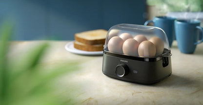 Taghareed Philips 3000 Series HD9137/91 black egg cooker with 6 eggs inside, clear lid, and toast in background.
