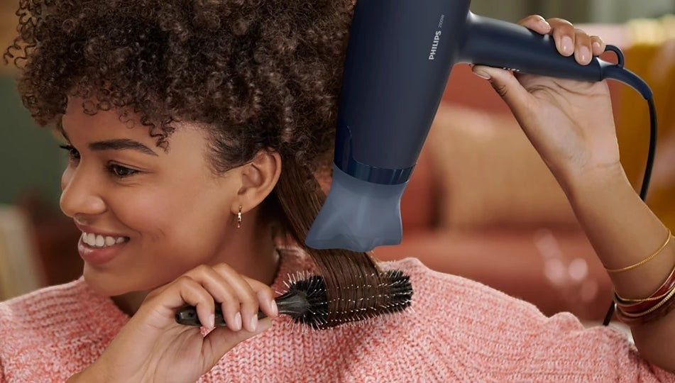 Taghareed Philips 3000 Series dark blue hair dryer with ThermoProtect attachment drying woman's brown hair.
