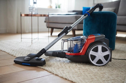 Taghareed Philips PowerPro Compact bagless vacuum cleaner in red and black with a MultiClean nozzle on a rug.
