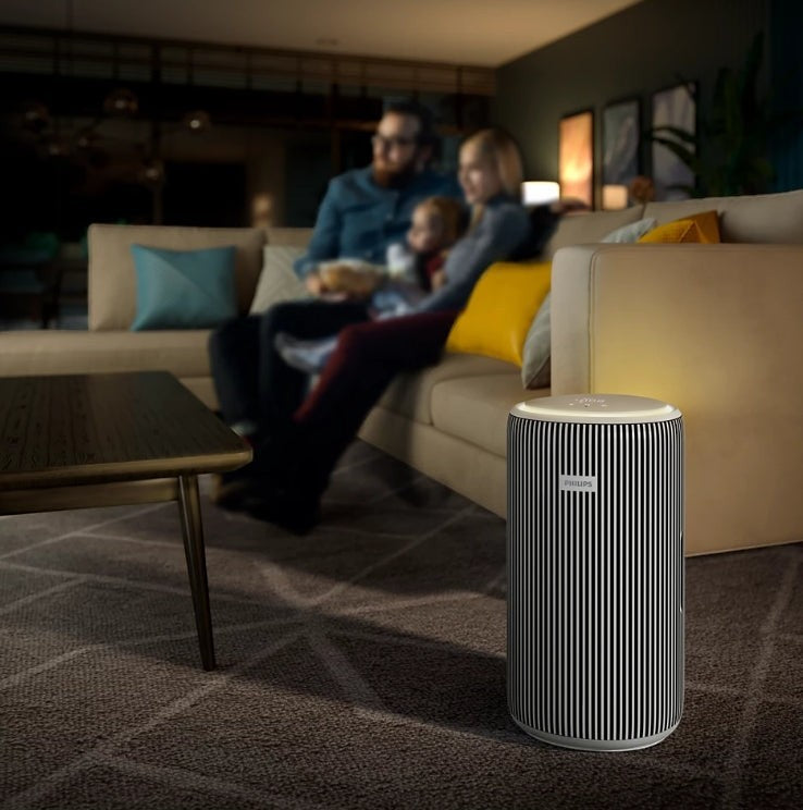 Philips PureProtect 3200 Series AC3220/10 air purifier with black and white striped design, in a living room setting with a family on the couch.