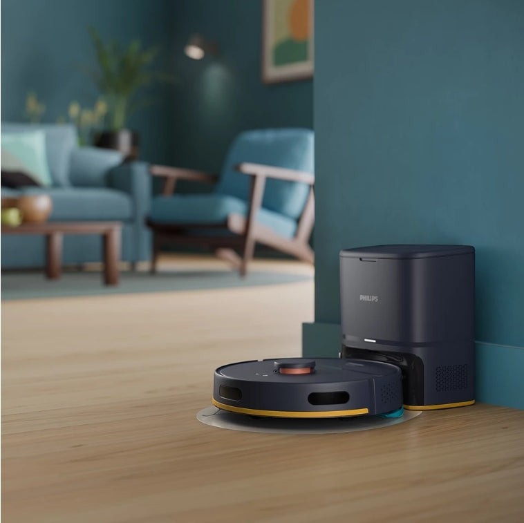 Taghareed Philips 2000 Series robot vacuum cleaner with auto-empty station, dark blue and yellow accents, cleans hardwood floors.