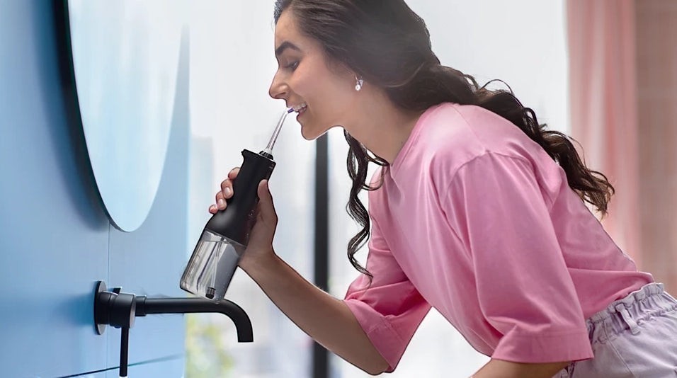 Taghareed Philips Sonicare Cordless Power Flosser 3000 HX3826/33 with 3 modes in black and clear, used by a woman.