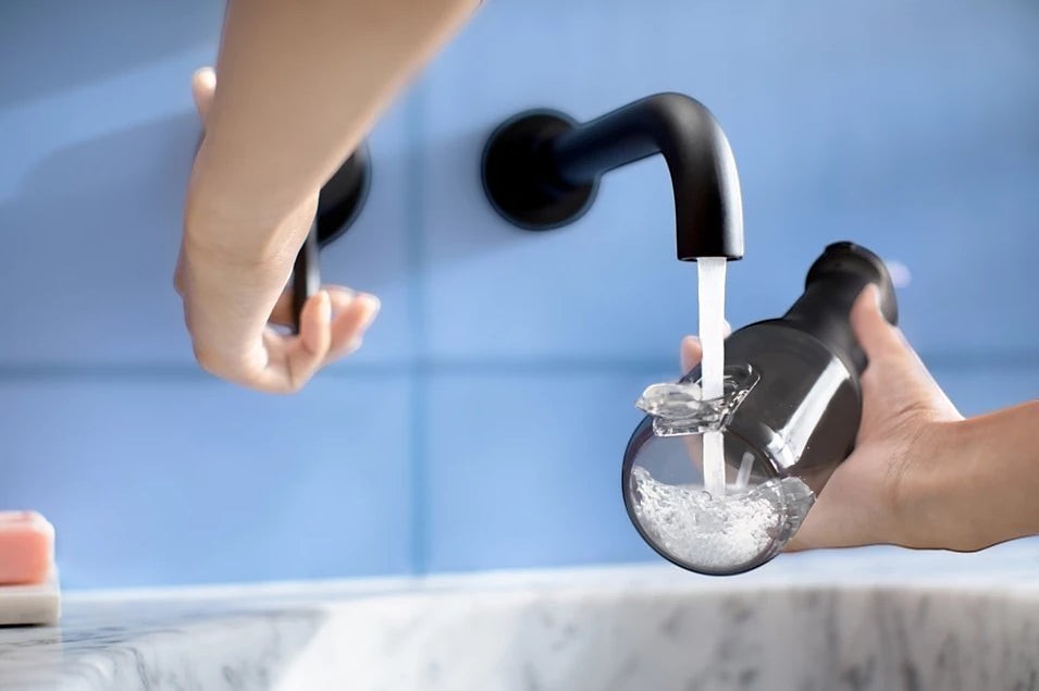 Taghareed Philips Sonicare Cordless Power Flosser 3000 HX3826/33 filling with water from a faucet. Black oral irrigator with 3 modes.