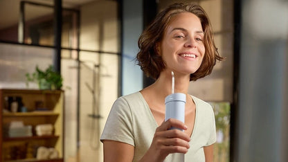 Taghareed Philips Sonicare Compact Flosser 1000 HX3333/24 cordless water flosser with 3 modes, light blue, in use by a smiling woman.