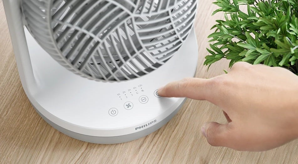 Taghareed Philips Table Fan 2000 Series CX2050/00 white plastic with 3 speeds, timer, and 2 modes. A hand presses a button on the base.