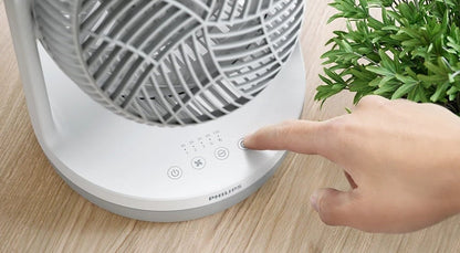Taghareed Philips Table Fan 2000 Series CX2050/00 white plastic with 3 speeds, timer, and 2 modes. A hand presses a button on the base.